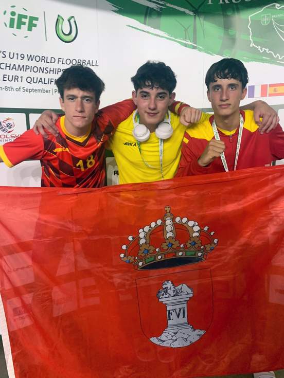 Tres deportistas de Floorball de Guadarrama con la bandera de la localidad en Polonia